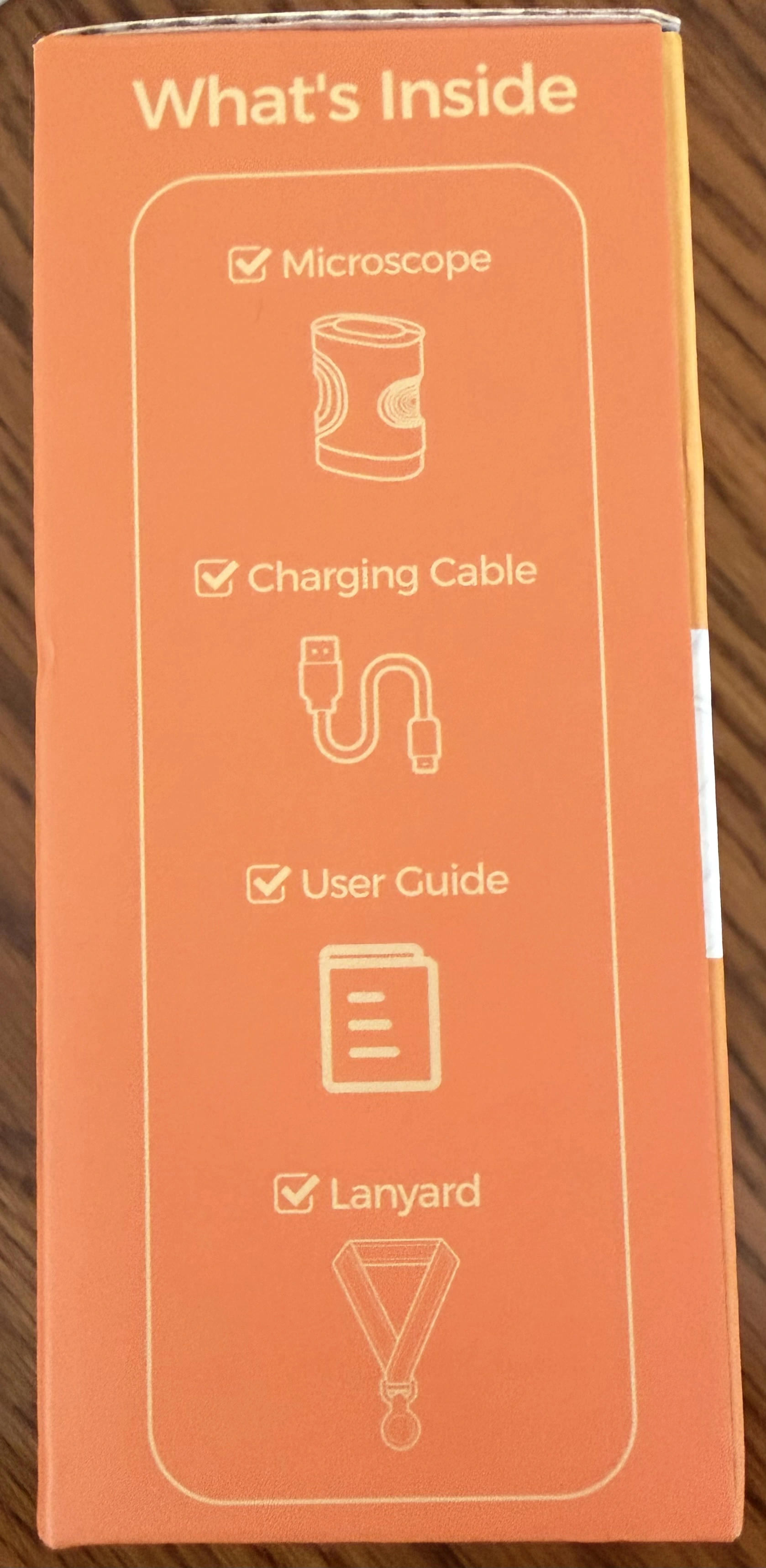 Side of the WonderQuest box listing the contents: microscope, charging cable, user guide and lanyard