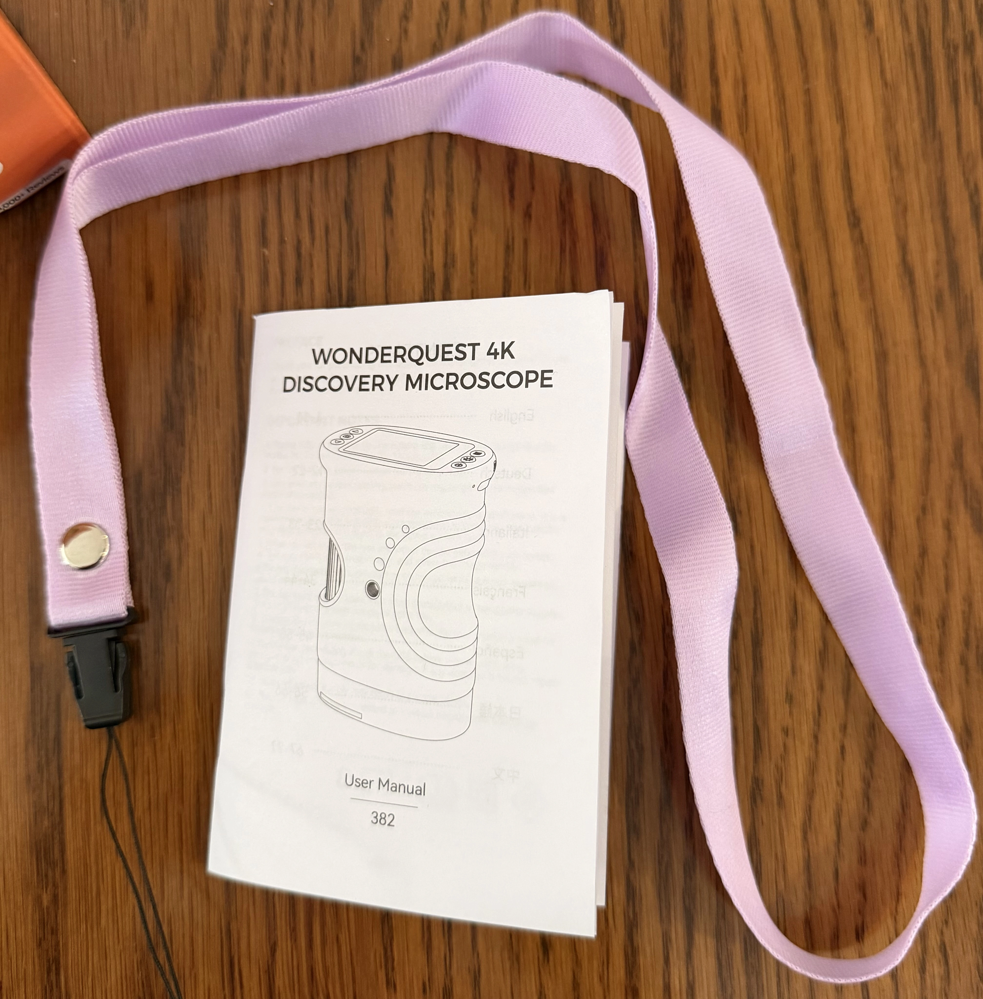 WonderQuest 4K Discovery Microscope user manual and pink lanyard, with "382" printed on the cover below the title